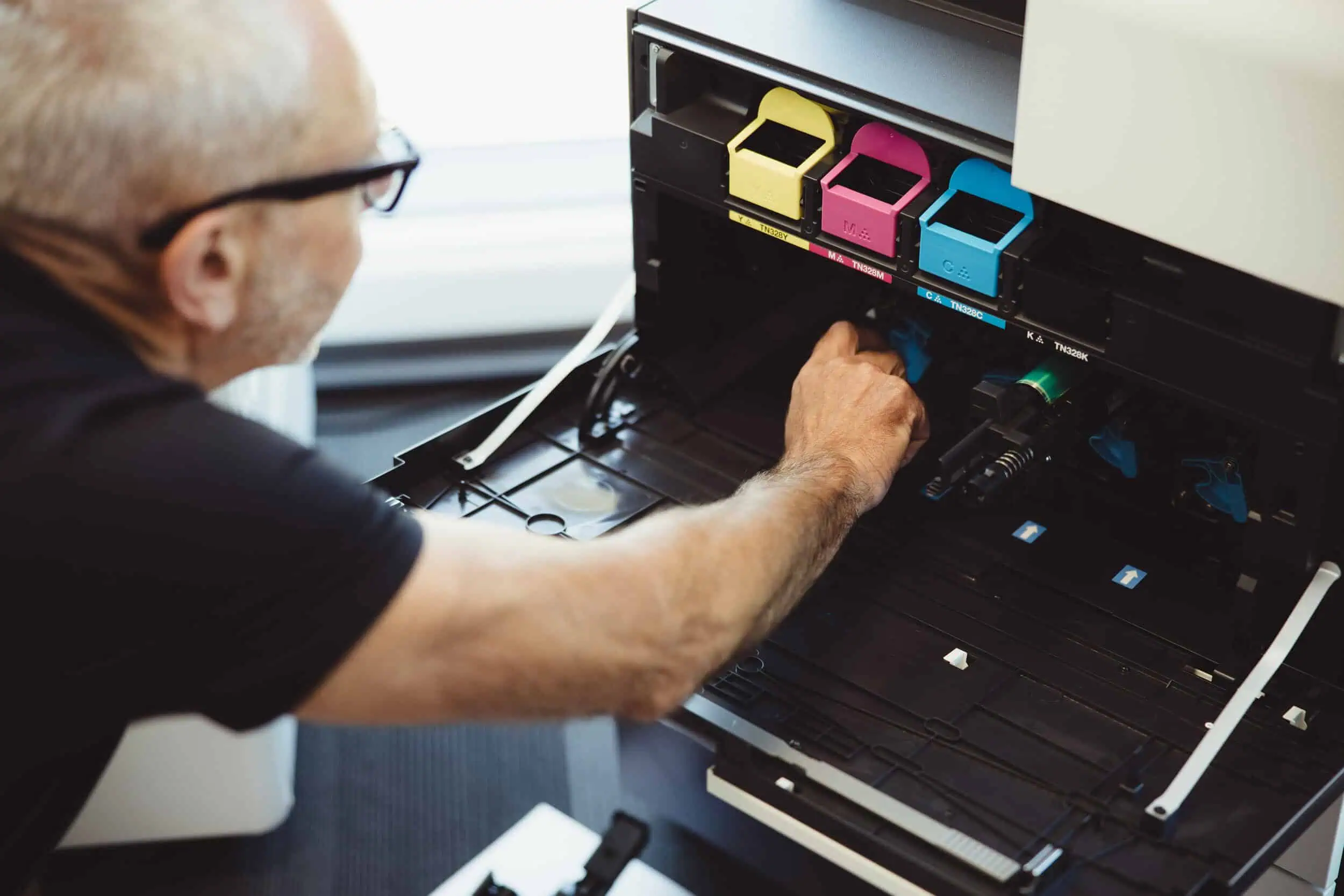 DUPLIQ engineer wearing glasses installing toner cartridges into a printer
